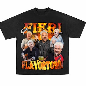 Op de afbeelding: Zwart T-shirt met een vintage-stijl afbeelding van Guy Fieri. De afbeelding bevat meerdere afbeeldingen van Fieri met de tekst "Guy Fieri" en "Flavortown" in een vet, geel lettertype.