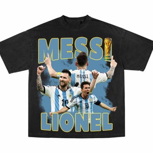 Puede incluir: Camiseta negra con un gr&aacute;fico de estilo vintage de Lionel Messi celebrando con el trofeo de la Copa Mundial. El gr&aacute;fico presenta m&uacute;ltiples im&aacute;genes de Messi con su camiseta de Argentina, con el texto "MESSI LIONEL" en letras grandes y en negrita.