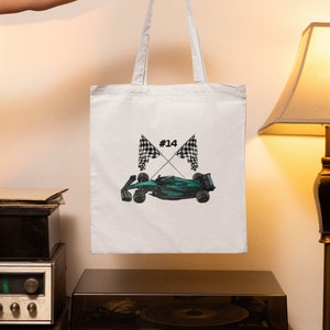 May include: White tote bag with a green race car and checkered flags printed on it. The car has the number "#14" on it.