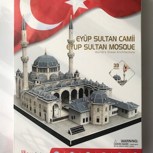 Könnte beinhalten: Ein 3D-Puzzle der Eyüp-Sultan-Moschee in Istanbul, Türkei. Die Schachtel zeigt eine rote türkische Flagge mit einem weißen Halbmond und Stern. Das Puzzle besteht aus 150 Teilen und ist 45 x 30,5 x 31 cm groß. Es ist ein 3D-Puzzle der Eyüp-Sultan-Moschee in Istanbul, Türkei. Die Schachtel zeigt eine rote türkische Flagge mit einem weißen Halbmond und Stern. Das Puzzle besteht aus 150 Teilen und ist 45 x 30,5 x 31 cm groß.