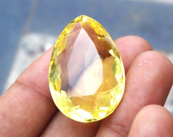 May include: A teardrop-shaped, faceted, yellow gemstone.