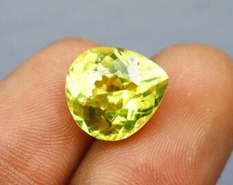 May include: A pear-shaped, faceted gemstone with a vibrant lemon-yellow color. The stone features a brilliant cut with numerous triangular and kite-shaped facets that reflect light, creating a bright, sparkling appearance throughout the surface.