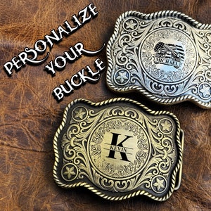 May include: Two rectangular metal belt buckles with ornate scrollwork and rope-style borders. The top buckle features a flag and gun graphic with the name MICHAEL. The bottom buckle displays a large letter K with the name KEVIN. Text reads PERSONALIZE YOUR BUCKLE.