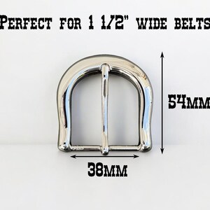 May include: Silver metal belt buckle measuring 1 1/2 inches wide. The buckle is 54 mm tall and 38 mm wide.