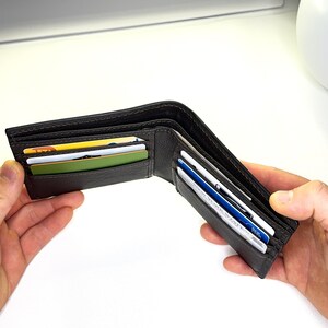May include: A brown leather wallet with multiple card slots, open and displaying several cards inside.