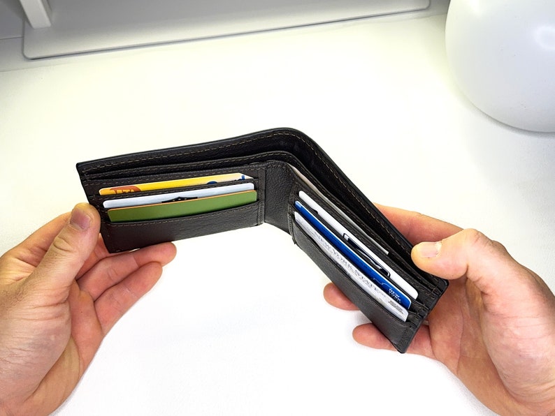 May include: A brown leather wallet with multiple card slots, open and displaying several cards inside.
