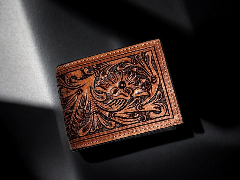 May include: A brown leather wallet with an intricate floral design embossed on the front.
