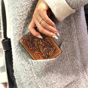 May include: A brown leather wallet with a floral design and the name "Amy" embossed on the front.