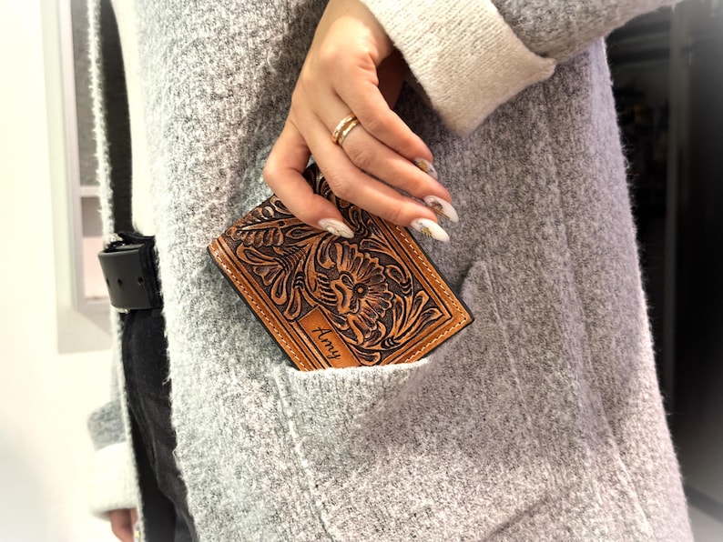 May include: A brown leather wallet with a floral design and the name "Amy" embossed on the front.