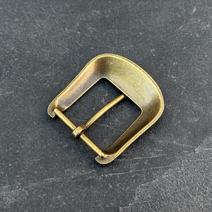 Puede incluir: Hebilla de cintur&oacute;n de lat&oacute;n de estilo vintage con un marco rectangular y una parte superior curvada. La hebilla tiene un dise&ntilde;o cl&aacute;sico con un pasador para asegurar el cintur&oacute;n. El metal tiene un aspecto ligeramente envejecido.