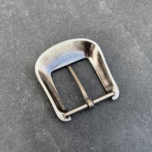 Puede incluir: Hebilla de cintur&oacute;n de metal plateado, de forma rectangular con una barra central. La hebilla tiene un acabado ligeramente desgastado, lo que le da un aspecto vintage. Dise&ntilde;ada para usar con un cintur&oacute;n.