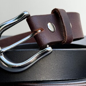 May include: A brown leather belt with a silver buckle. The belt is folded in half and the buckle is visible.