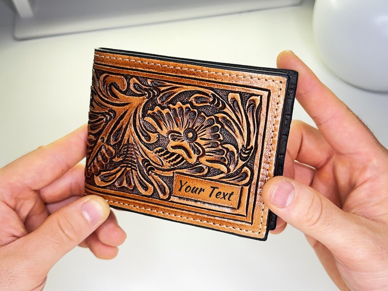 May include: A brown leather wallet with a floral design and a black border. The wallet has a space for personalization with the text "Your Text".