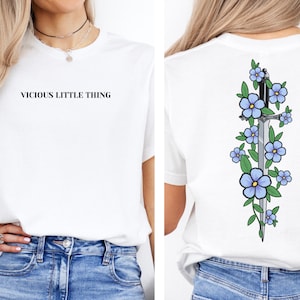 May include: White t-shirt with the text "Vicious Little Thing" on the front and a sword with blue flowers on the back.