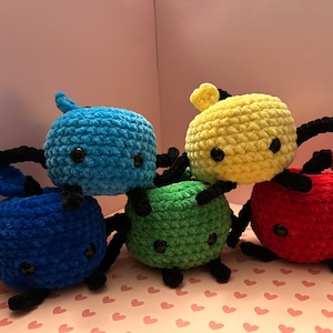 Könnte beinhalten: Fünf gehäkelte Plüschtiere in Form einer Krabbe. Die Krabben sind blau, grün, gelb, rot und dunkelblau. Sie haben schwarze Augen und Beine.
