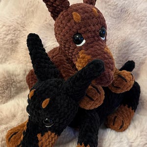 May include: Two crocheted plush dog toys. One is brown with tan accents and the other is black with tan accents.