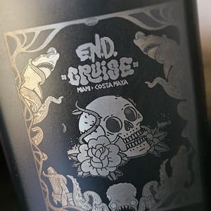 May include: Black flask with a screw-on cap. The flask features an engraved design with the words "END. CRUISE" above "MIAMI > COSTA MAYA". The design includes a skull, flower, and sea creatures.