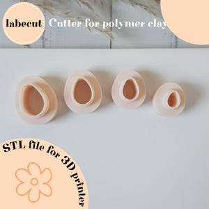 Puede incluir: Un conjunto de cuatro cortadores de arcilla polimérica rosa claro con forma ovalada. Los cortadores tienen un borde exterior elevado y una forma interior redondeada. El texto "labecut Cutter for polymer clay" está en la parte superior.