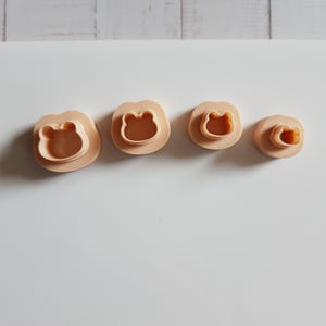 Könnte beinhalten: Ein Set aus drei Keramikbechern mit gesprenkelter, matter Oberfläche. Die Becher sind in den Farbtönen Creme, Hellgrau und Dunkelgrau gehalten. Jeder Becher hat ein schlichtes, minimalistisches Design, geeignet für Kaffee oder Tee.