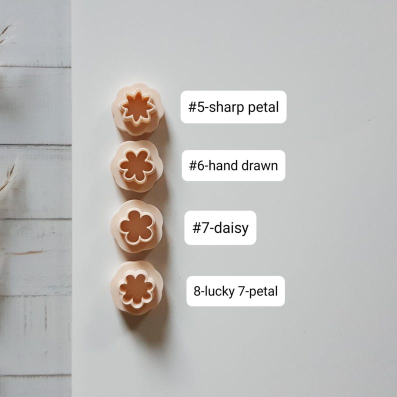 Pu&ograve; includere: Quattro formine per biscotti beige a forma di fiore con diversi disegni di petali. L'immagine include etichette di testo: "#5-sharp petal", "#6-hand drawn", "#7-daisy" e "8-lucky 7-petal". Ideali per la cottura e l'artigianato.