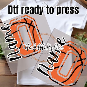 May include: Two iron-on transfers featuring a basketball design with the word "Name" in black text. The transfers are ready to press onto a shirt or other fabric.