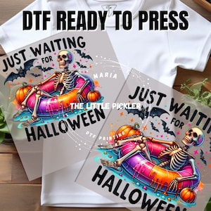 May include: A digital transfer design featuring a skeleton in a colorful inflatable ring with the text "Just Waiting for Halloween".