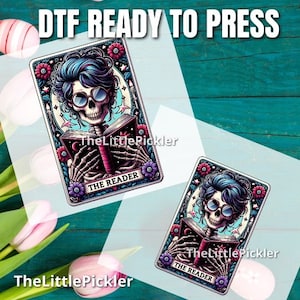 May include: A digital download of a printable design featuring a skeleton with blue hair reading a book. The design is framed with a colorful floral border and the text "The Reader".
