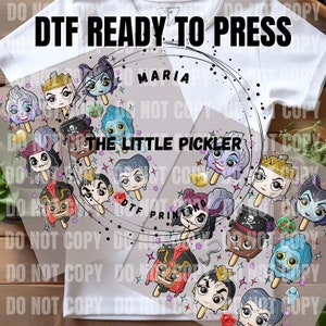 May include: A white t-shirt with a clear transfer sheet on top. The transfer sheet has a circular design with various cartoon characters from Disney movies. The characters are depicted as popsicles with dripping ice cream. The text "DTF READY TO PRESS" is at the top of the design. The text "MARIA" is at the top of the circle. The text "THE LITTLE PICKLER" is at the bottom of the circle.