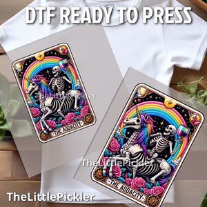May include: Two iron-on transfers featuring a skeleton riding a unicorn with a rainbow and stars in the background. The text "The Audacity" is on the bottom of each transfer.