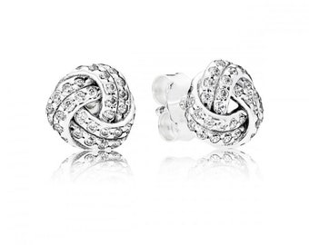 May include: Silver stud earrings with a knot design and clear cubic zirconia stones.