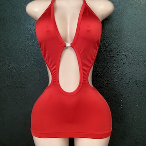 May include: A vibrant red halter dress with a plunging neckline and a keyhole cutout. The dress features a small, sparkling embellishment at the bust and a form-fitting silhouette. The dress is displayed on a mannequin.