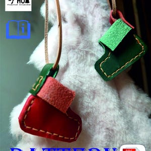 May include: A PDF pattern for making two leather Christmas stocking ornaments. One ornament is red and the other is green. The ornaments are hanging from a white fuzzy surface.