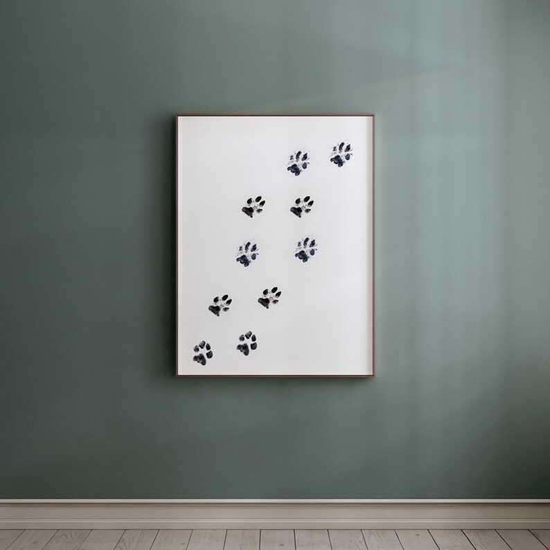 May include: A framed print with a white background and black paw prints in a diagonal pattern.