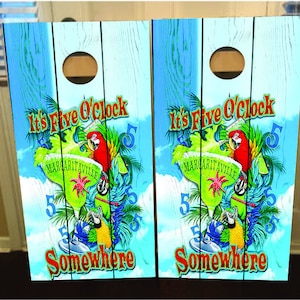 Puede incluir: Dos letreros de madera con un fondo de madera azul y blanco. Los letreros presentan un vaso de margarita verde con un loro rojo y el texto "It's Five O'Clock Somewhere" y "Margaritaville".