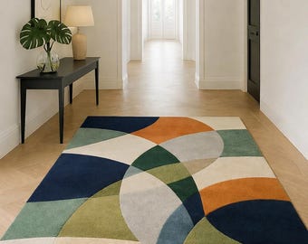 May include: A colorful geometric area rug with a modern design. The rug features a pattern of overlapping arcs in shades of navy blue, green, orange, and beige. It is placed on a light-colored wooden floor in a hallway.