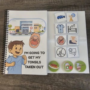 Pode incluir: Um livro de programação visual com espiral com ilustrações para uma visita ao hospital. A capa mostra uma criança e uma cena hospitalar. O texto diz "VOU TIRAR AS AMÍGDALAS". Auxílios visuais adicionais estão incluídos.