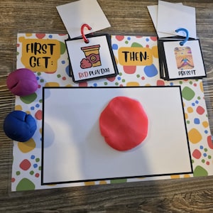 Könnte beinhalten: Ein farbenfrohes Lernspielset mit den Texten "FIRST GET:" und "THEN:" und visuellen Anweisungen. Enthält rote und blaue Knete sowie Karten mit Bildern und Texten wie "RED PLAY DOH" und "PRESS IT".