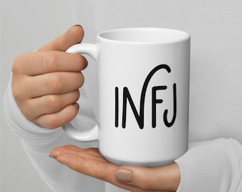 May include: White ceramic mug with a black graphic of the letters "INFJ" in a stylized font.