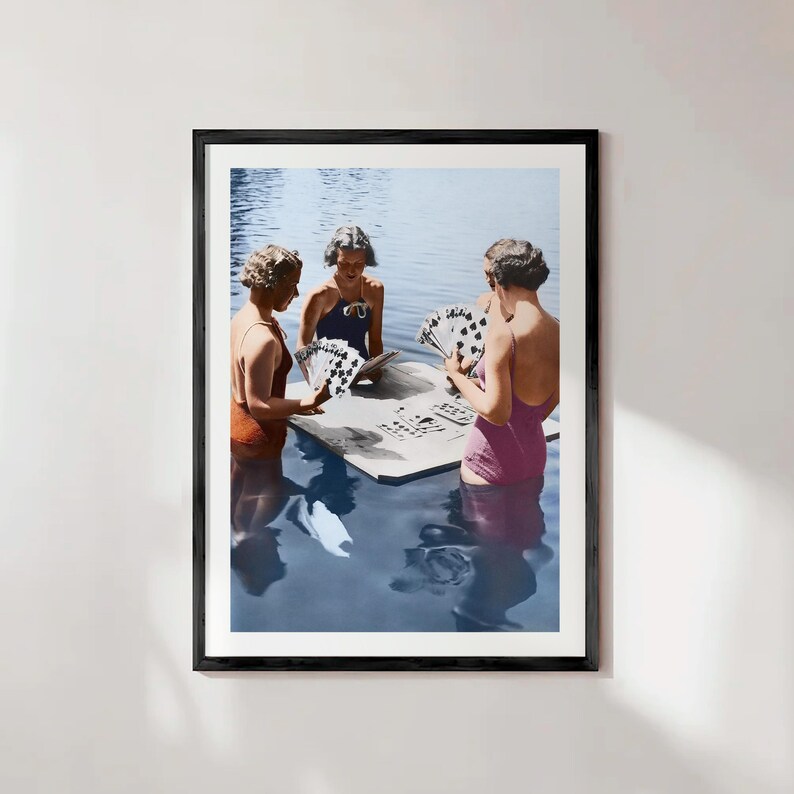 Puede incluir: Impresi&oacute;n enmarcada que presenta a tres mujeres con trajes de ba&ntilde;o vintage jugando a las cartas en el agua. Las mujeres est&aacute;n de pie en el agua, reunidas alrededor de una mesa con naipes. La impresi&oacute;n tiene un aire vintage y nost&aacute;lgico.