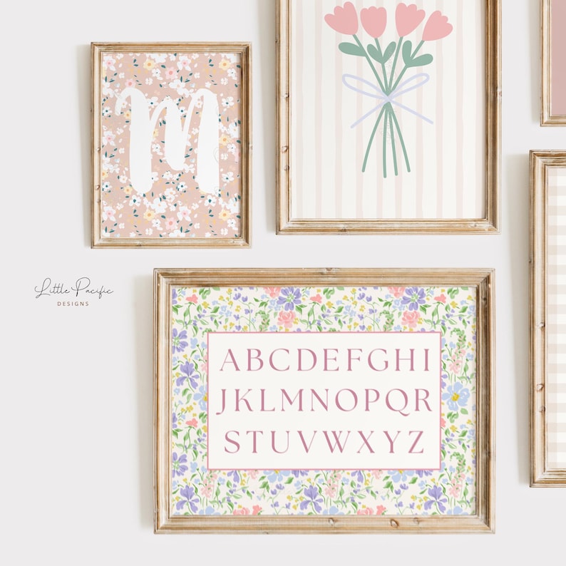 May include: A collection of framed floral art prints. One print features the letter "M" in white over a floral pattern. Another displays a bouquet of pink flowers. A third print has the alphabet in a pink box.