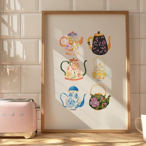 Puede incluir: Una impresión enmarcada con seis ilustraciones de acuarela de teteras con varios patrones florales y geométricos. Las teteras están dispuestas en dos filas de tres, cada tetera tiene un diseño único. El fondo es de color crema claro.