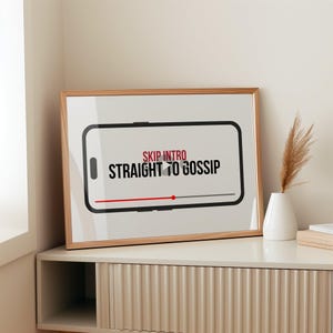 Peut inclure: Une affiche encadrée avec le texte "SKIP INTRO STRAIGHT TO GOSSIP" en noir et rouge. Le design ressemble à un écran de téléphone avec une barre de lecture. Le cadre est de couleur marron clair, et l'affiche est affichée sur une surface blanche.