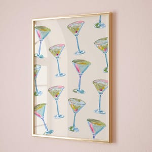 Könnte beinhalten: Ein gerahmter Druck mit einem sich wiederholenden Muster aus bunten Martini-Gläsern auf weißem Hintergrund. Die Gläser sind in Blautönen, Grün, Rosa und Gelb bemalt.