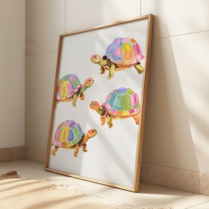 Op de afbeelding: Een ingelijst drukwerk met vier kleurrijke schildpadden met geometrische patronen op hun schilden. De schildpadden zijn geschilderd in tinten roze, blauw, groen en geel op een witte achtergrond.