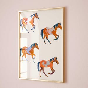 May include: A framed print featuring four stylized horses in shades of orange, brown, and white against a white background. The horses are depicted in a dynamic, energetic pose, with their manes and tails flowing in the wind.
