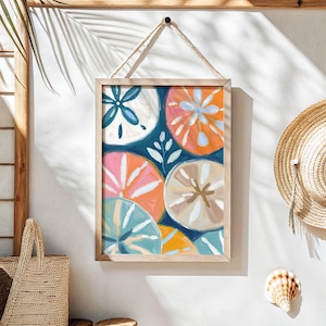May include: A framed print with a blue background featuring a colorful abstract design of sand dollars. The sand dollars are painted in shades of pink, orange, yellow, and blue.