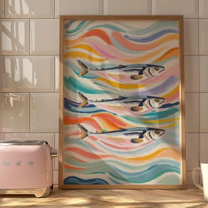 May include: A framed print of three fish swimming through colorful, abstract waves. The fish are painted in a realistic style, while the waves are painted in a more abstract style. The colors are bright and vibrant, and the overall effect is cheerful and whimsical.