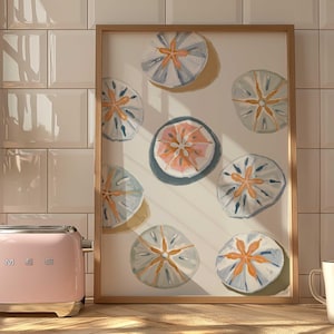 May include: A framed print of a painting featuring a white background with nine sand dollars in various shades of blue, orange, and white.