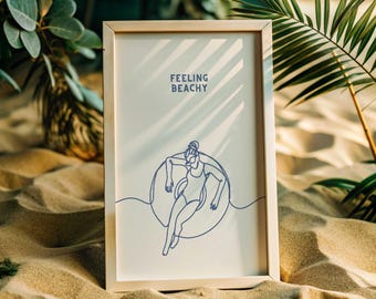 May include: A framed print with a white background and a blue line drawing of a person relaxing in a pool float. The text "Feeling Beachy" is printed in blue at the top of the print.