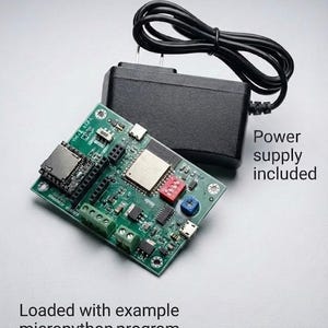 May include: A green circuit board with various electronic components, including a micro SD card slot, red and blue switches, and a USB port. A black power supply is connected to the board. Text on the image reads "Power supply included" and "Loaded with example micropython program."
